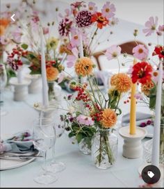 a table topped with lots of vases filled with different types of flowers and candles