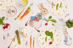 a table topped with plates and utensils filled with vegetables, carrots and broccoli