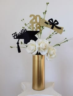 a gold vase filled with white flowers on top of a table