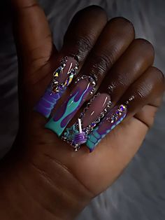 a woman's hand with purple and blue nail polishes on her nails,