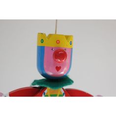 a colorful clown ornament hanging from a string in front of a white wall