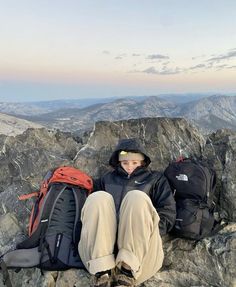 a person sitting on top of a mountain with backpacks