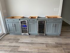 two wine coolers in the middle of a kitchen with wood flooring and white walls