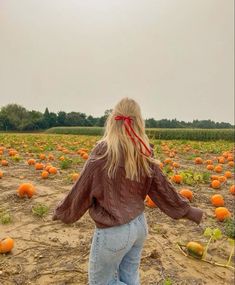 a woman is walking through a pumpkin patch