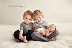 two young children sitting on top of a bed holding their babies