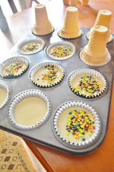 cupcake tins are lined up on a baking tray with candy sprinkles