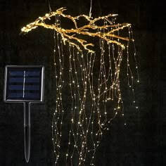 a solar powered light hanging from the side of a tree with branches and lights attached to it