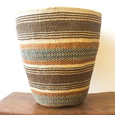 a large woven basket sitting on top of a wooden table next to a white wall