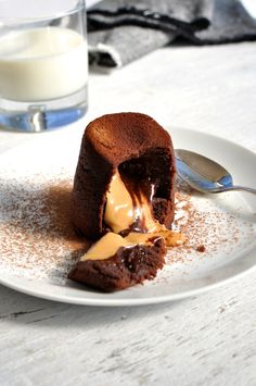 a piece of chocolate cake on a plate with a spoon and glass of milk in the background