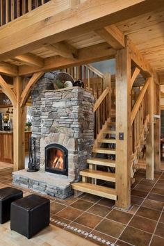 a living room with a stone fireplace and wooden staircase leading up to the second floor