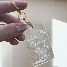 a person holding a keychain with the words ride em cowboy on it