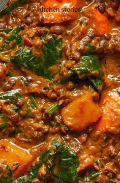 a bowl filled with meat and spinach covered in sauce on top of a table