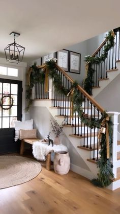 a staircase decorated for christmas with greenery and garland on the bannister railing