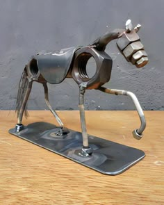 a metal horse sculpture sitting on top of a wooden table