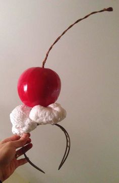 a person holding an object made out of marshmallows, cherries and whipped cream