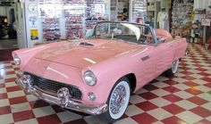 an old pink car is on display in a store