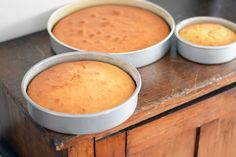 three pans of cake sitting on top of a wooden table