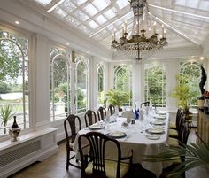 a dining room table set with place settings and chairs, in front of large windows