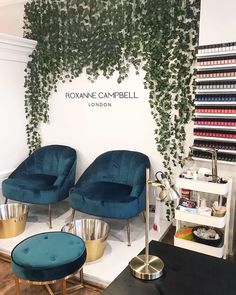 two blue chairs sitting next to each other in front of a wall covered with plants