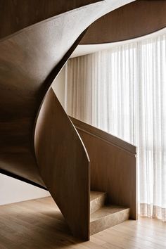 a wooden spiral staircase next to a window