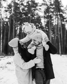 a man and woman walking in the snow with a child on their shoulders, holding onto each other