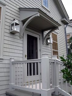 the front porch of a house with white railings and two lights on each side