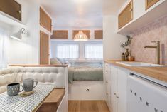 a small kitchen and dining area in a tiny home with white cabinets, wood flooring and pink patterned wallpaper