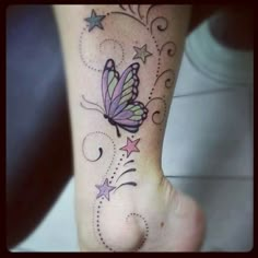 a small butterfly tattoo on the foot with stars and swirls around it's wings