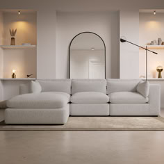 a large white couch sitting in a living room next to a mirror