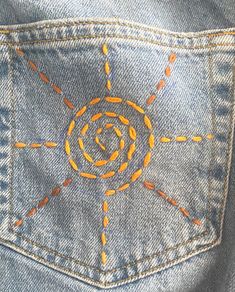 the back pocket of a pair of jeans with an orange and yellow design on it