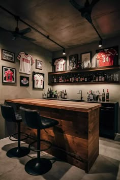 a bar with two stools in front of it and pictures on the wall behind it