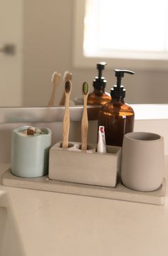 a bathroom counter with toothbrushes and soap dispensers on it's tray