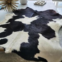 a black and white cowhide rug sitting on top of a table next to a vase