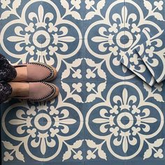 a person standing on a tile floor next to a blue and white flowered design