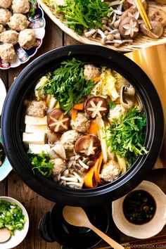 an assortment of food is displayed in bowls on a wooden table with chopsticks