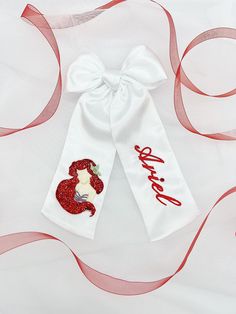 White satin bow with Ariel embroidery on it and a custom name. This bow also has glitter attached to it as well as crystals. Ariel Embroidery, Embroidery Hair Bow, Mermaid Bow, Embroidery Hair, Embroidery Bow, Sell Ideas, Pearl Embroidery, Future Mom, Satin Bow