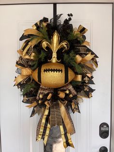 a gold and black football wreath on the front door with a fleur de lis decoration