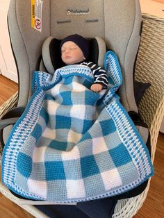 a baby sleeping in a car seat covered with a blanket