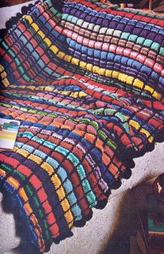 a multicolored crocheted blanket sitting on top of a bed