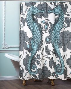 the shower curtain is decorated with blue and gray floral designs, along with a claw foot bathtub