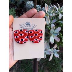 a hand holding up a pair of red and black polka dot clip on top of a card