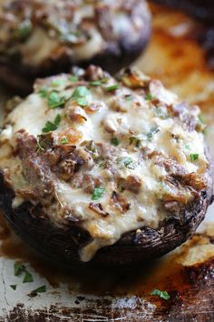 two stuffed mushrooms covered in cheese and herbs