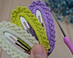 there are crocheted hair clips being held by someone's hand with a knitting needle