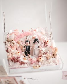 a wedding cake topper in a clear box with pink flowers and pearls on it