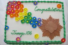 a cake decorated with flowers and congratulations written on the side, in green icing