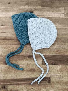 two crocheted hats sitting on top of a wooden floor