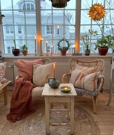 a living room filled with lots of furniture next to a window covered in plants and candles