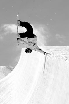 a man riding a snowboard up the side of a ramp on a skateboard