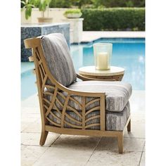 a chair next to a swimming pool with a candle on the end table in front of it