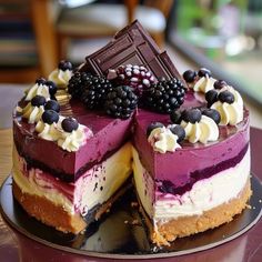 there is a cake that has been cut in half and topped with blueberries, raspberries, and chocolate